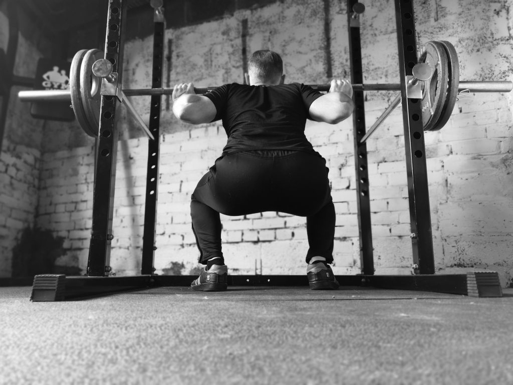 A man doing squats using a folding squat rack