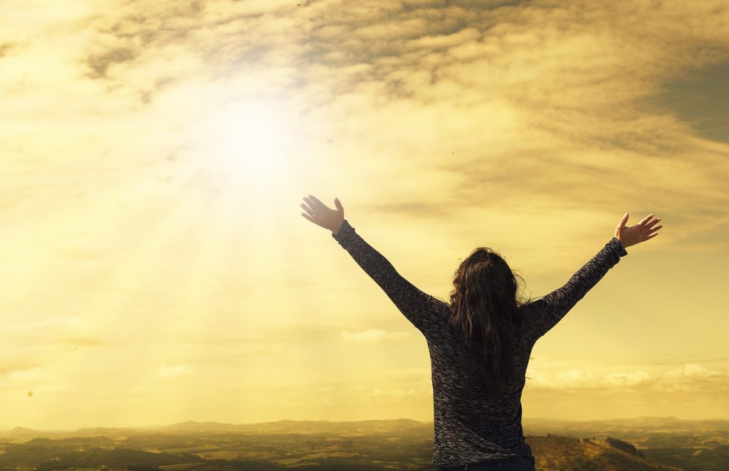 A person looking towards the sun with open arms ready to make a mindset shift for personal transformation