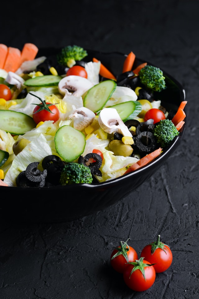 A bowl filled with a vegetarian salad that includes mushrooms, broccoli, cucumber, and corn all playing a role in the nutritional needs for vegetarians.