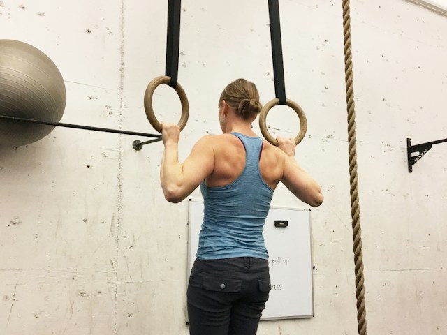 A woman performing pullups as a part of her back workout