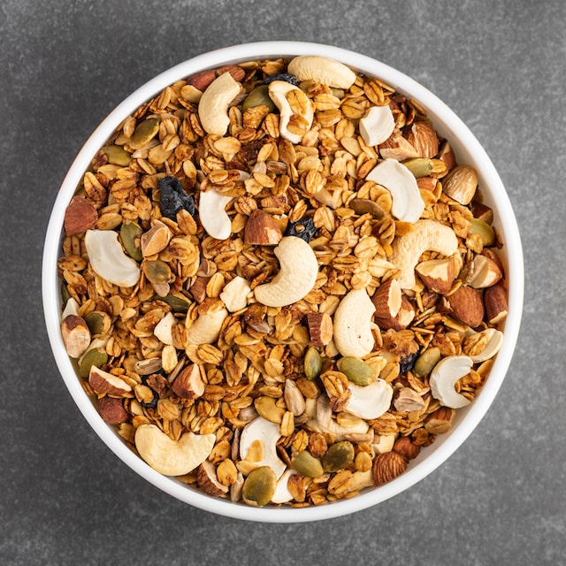 A bowl filled with nuts, quinoa, coconut, and barries which are all some of the best anti-inflammatory foods.