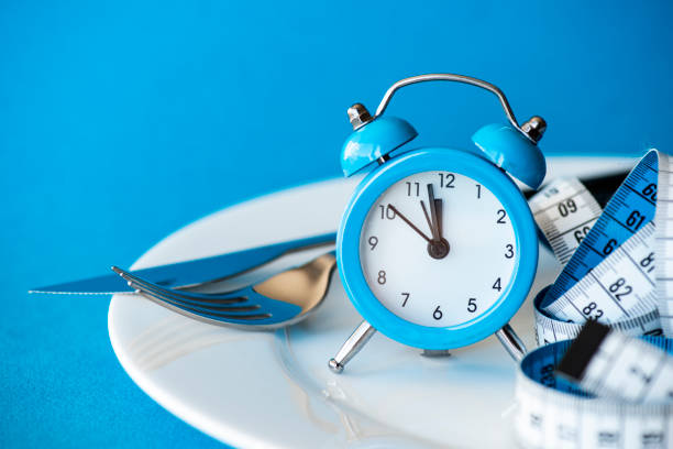 An empty plate with a watch and a measuring tape on it symbolising intermittent fasting.